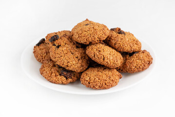 Oatmeal cookies with raisins in a white plate on a light table.