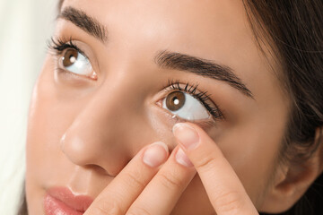 Woman putting contact lens in her eye, closeup view