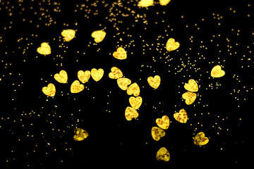 Golden blurred bokeh lights on black background. Glitter sparkle hearts for celebrate. Overlay for your design