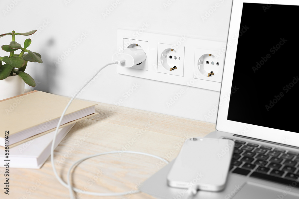 Wall mural laptop and smartphone charging on wooden table