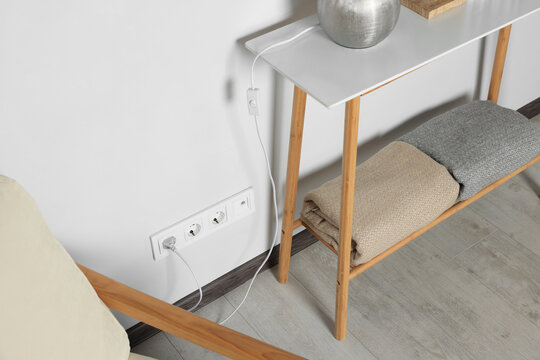 Electric power outlet sockets and plug on white wall indoors