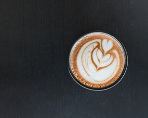 Espresso coffee cup top down picture in black background with heart art mixed with milk. Barista coffee art with latte milk on top. Delicious espresso latte coffee wallpaper.	