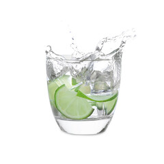 Water with sliced lime splashing out of glass on white background