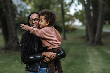 Black mother holding biracial son at park 