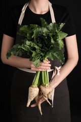 Woman holding sugar beets on black background, closeup