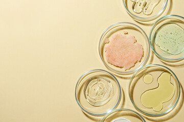 Many Petri dishes and cosmetic products on beige background, flat lay. Space for text