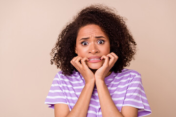 Photo of scared shocked lady wear violet t-shirt biting fingers isolated beige color background