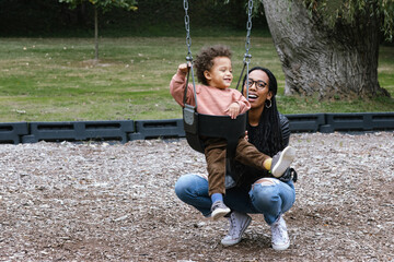 Mother pushing toddler on swing at park