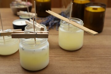 Glass jars with wax on wooden table, space for text. Handmade candles