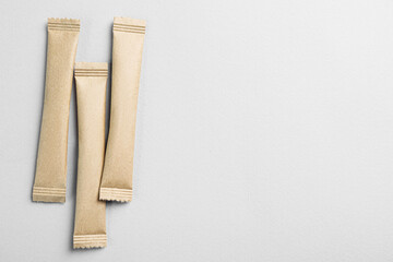 Beige sticks of sugar on light grey background, flat lay. Space for text