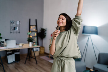 Happy woman dancing and singing at home