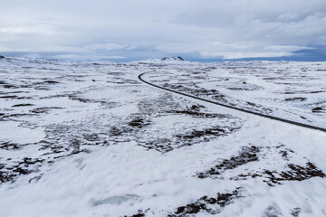 Empty asphalt road amidst field covered in snow