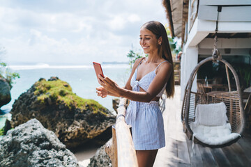 Happy woman taking selfie on smartphone in seaside cafe
