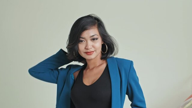 Attractive Asian woman wearing classic outfit posing for photographer at studio while shooting new clothing collection for lookbook