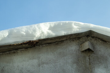 Snow drift on the metal roof of the garage after a snowfall. Close-up. Blue clear sky in the background
