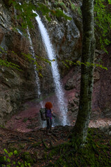 Obraz premium Woman nature photographer with camera by a waterfall