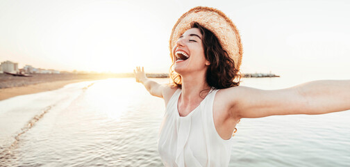 Happy woman with arms outstretched enjoying freedom at the beach  - obrazy, fototapety, plakaty