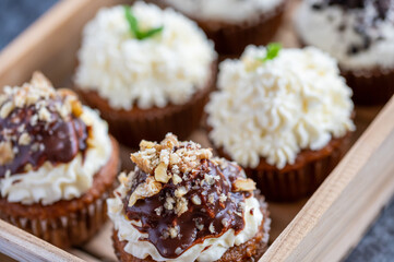 Cupcakes and muffins placed in wooden box. Chocolate and creme with nuts. Fresh home make baked sweets.