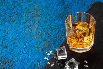 Glass of golden whiskey with ice. Strong alcoholic drink background