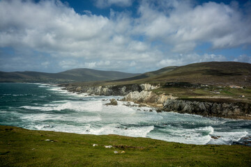 White Cliffs of Ashleam, on the Wild Atlantic Way on Achill Island, County Mayo, Ireland. Wild waves with white caps crash against the high rocks on the coast.