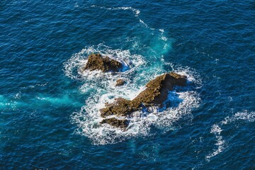 Naklejka premium Rocky formation in the middle of the sea surrounded by cristaline sea waters 