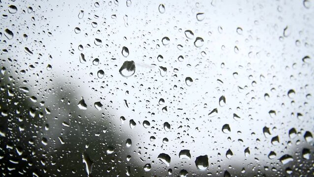 Raindrops on the glass. It's raining outside. Drops flow down the glass.