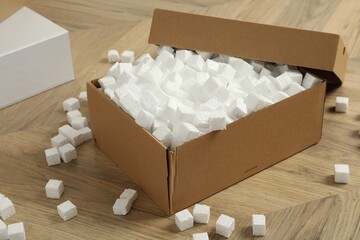 Cardboard box and styrofoam cubes on wooden floor