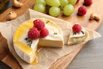 Brie cheese served with berries and honey on wooden table