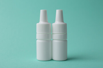 Bottles of medical drops on turquoise background