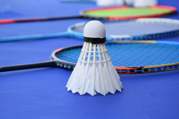 Cream white badminton shuttlecock and racket on floor in indoor badminton court, copy space, soft and selective focus on shuttlecocks.	