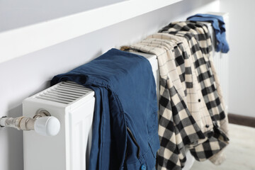 Clothes hanging on white radiator in room