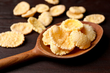 Spoon of tasty crispy corn flakes on wooden table, closeup