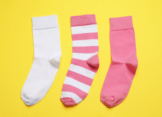 Different pink and white socks on yellow background, flat lay