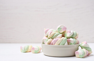 Bowl with colorful marshmallows on white table. Space for text