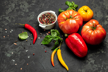 Various colorful garden tomatoes, bell peppers and spices. Ingredients for cooking on a dark...