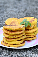 closeup the bunch yellow brown bengal gram fried food with green mint in the plate soft focus natural grey brown background.