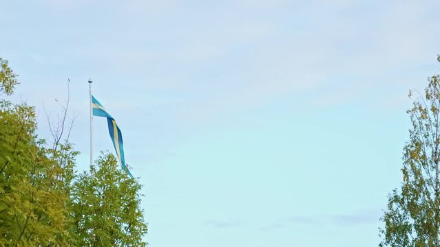 Swedish flag blowing in the wind. National flag of Sweden under a cloudy sky. Slow motion 4k video.