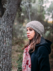 Hermosa mujer joven con chaqueta y gorro disfrutando de días otñoales en el monte.