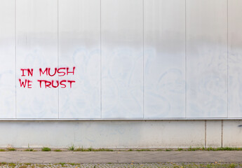 Graffiti "In Mush We Trust", red writing sprayed on white house wall, Berlin-Friedrichshain, Germany