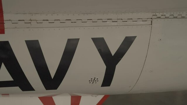 This panning video shows "navy" painted on the side of a white jet.
