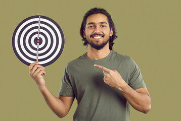 Happy Indian man holding target with concentric circles. Studio shot of ethnic entrepreneur in...