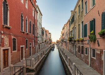 Fototapeta na wymiar Typical Venetian canal, early in the morning. Venice, Italy. The buildings are reflecting on the calm water