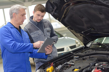 student with instructor repairing a car during apprenticeship