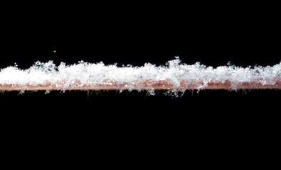 White snowflakes on a tube in winter isolated on a black background.