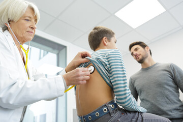 Fototapeta premium doctor examining a little boy with a stethoscope