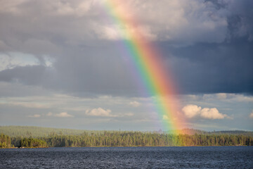 Rainbow with dramatic sky over forset and lake, Finland