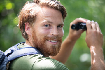 man with backpack holding binoculars