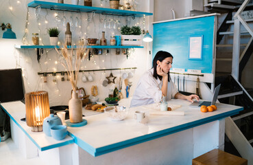Serious woman using netbook in kitchen