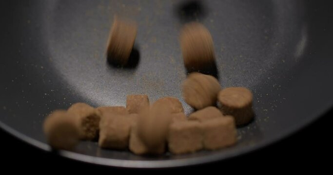 Dry dog or cat snack food is slowly poured into a black plate
