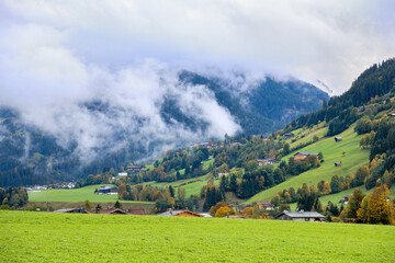 Morning mist rising over Alpine valley in autumn colorful countryside